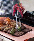 Forchetta barbecue in uso pratico con salsicce, hamburger e peperoni sulla griglia per cottura perfetta